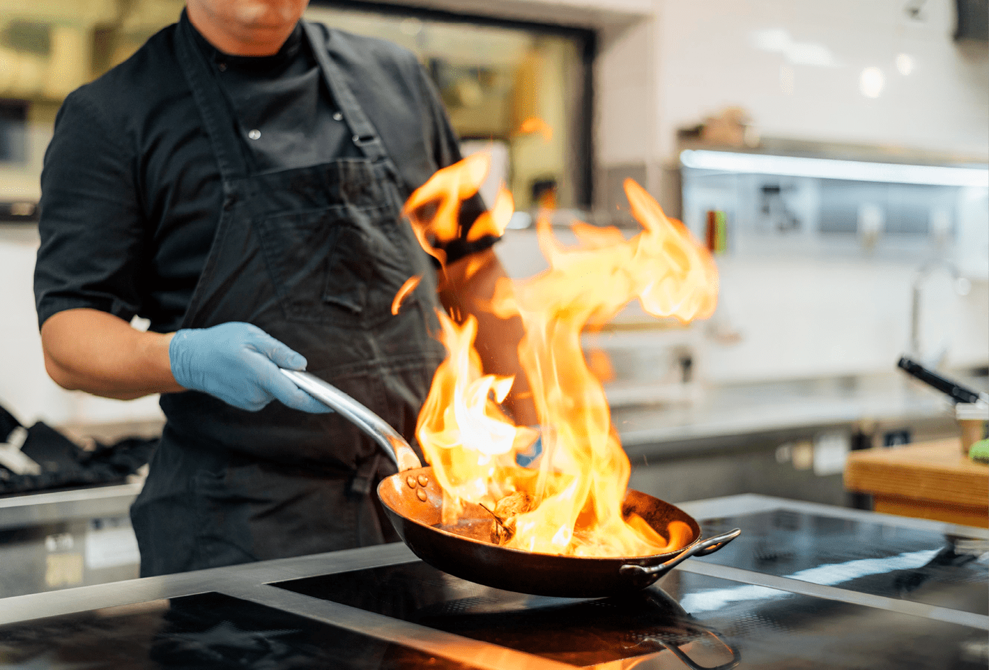chef with apron gloves flambeing dish