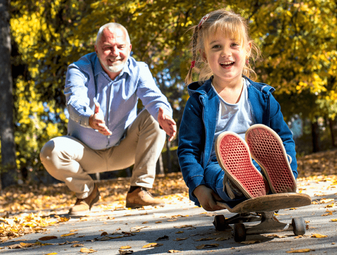 A smiling female grandchild playing with her grandfather in the park
