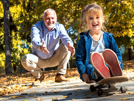 A smiling female grandchild playing with her grandfather in the park